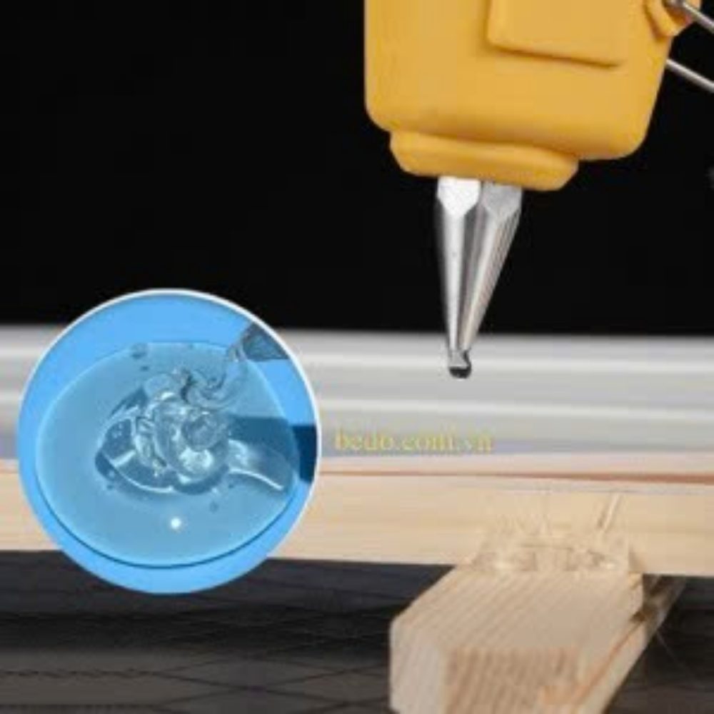 Đầu súng màu vàng đang ra keo nóng trên bề mặt gỗ
